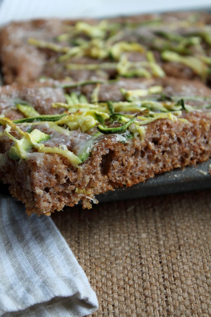 IL dettaglio di una fetta di focaccia integrale con zucchine e parmigiano

